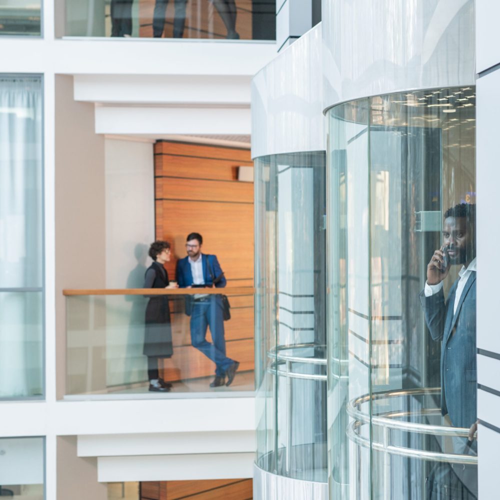 Modern interracial people working in business company: they talking to each other, black man communicating by phone